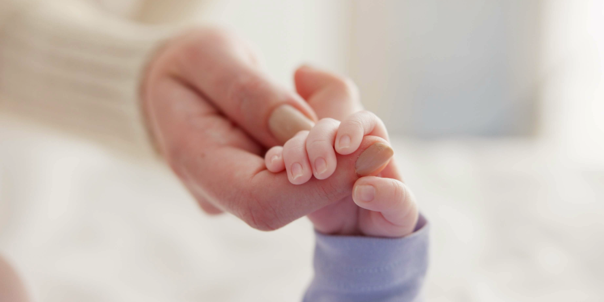 Bebé agarrándole dedo a su madre